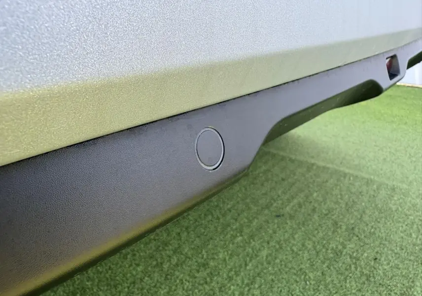 Gros plan sur le bas de caisse noir mat avec capteur de stationnement d'une Citroën C3 Rouge Elixir toit noir.