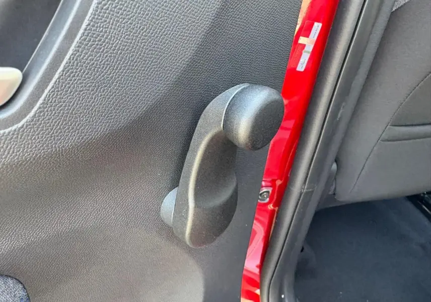 Poignée de lève-vitre manuel côté arrière gauche sur porte rouge Elixir d'une Citroën C3 IV New 2025.