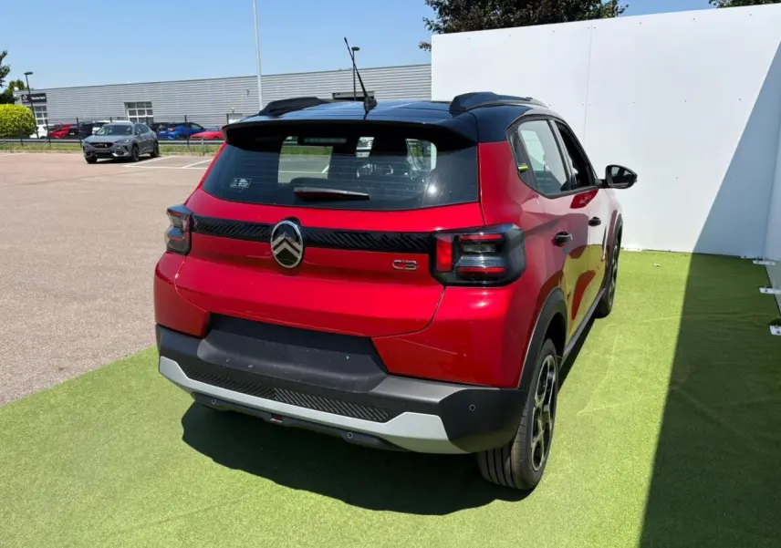 Vue 3/4 arrière droite d'une Citroën C3 2025 rouge Elixir avec toit noir et feux arrière fumés.
