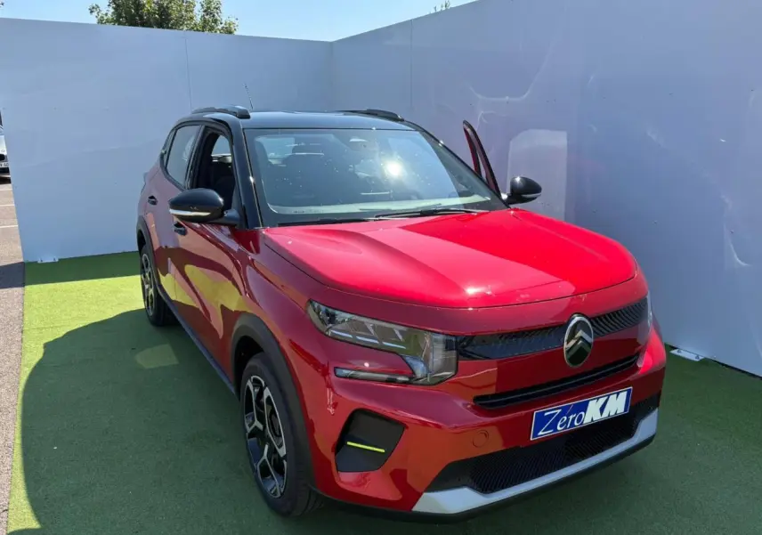 Citroën C3 2025 rouge Elixir avec toit noir, vue 3/4 avant droit, porte avant ouverte, jantes noires et grises.