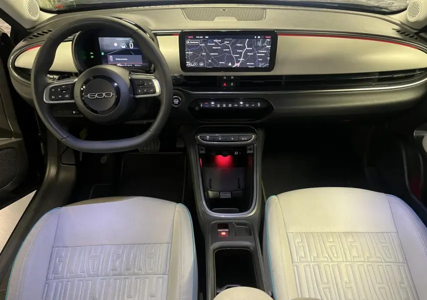 Vue intérieure avant de la Fiat 600 La Prima 2024 avec sellerie ivoire et tableau de bord ivoire et noir.