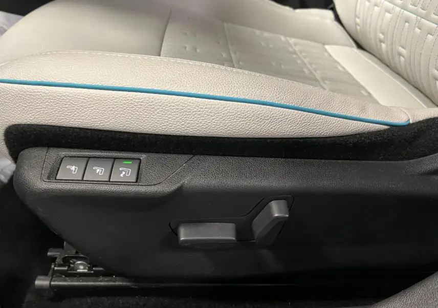 Gros plan sur les commandes électriques du siège conducteur ivoire avec surpiqûre bleue d'une Fiat 600 La Prima noire.