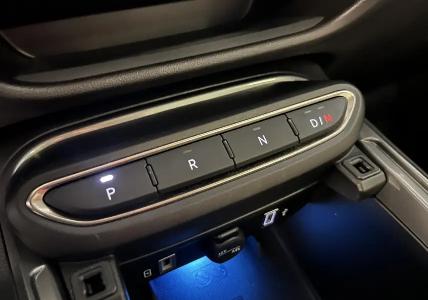 Gros plan sur la console centrale de la FIAT 600 La Prima 2024, avec boutons de boîte auto et éclairage bleu ambient.
