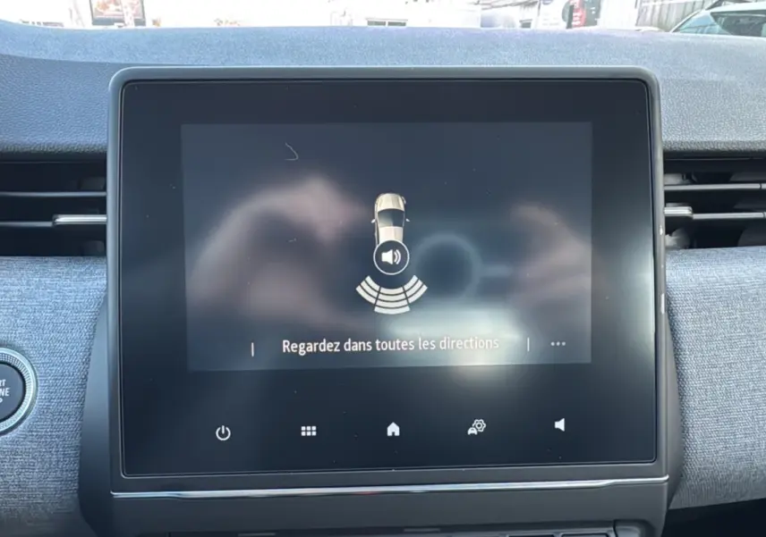 Écran tactile central du tableau de bord de la Renault Clio 2025, affichant une alerte de surveillance des angles morts.