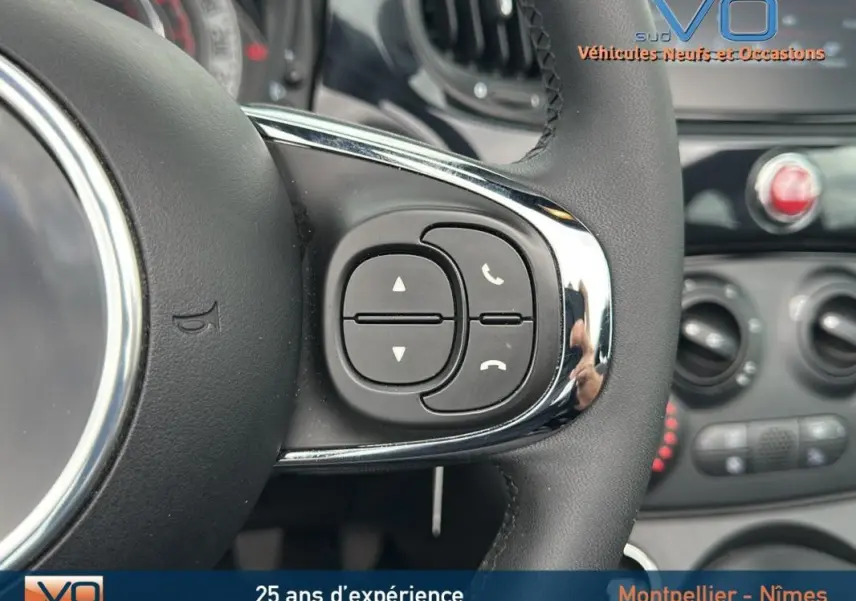 Gros plan sur les commandes du volant d'une FIAT 500C noire 2024, mettant en valeur les boutons de gestion d'appels et volume.