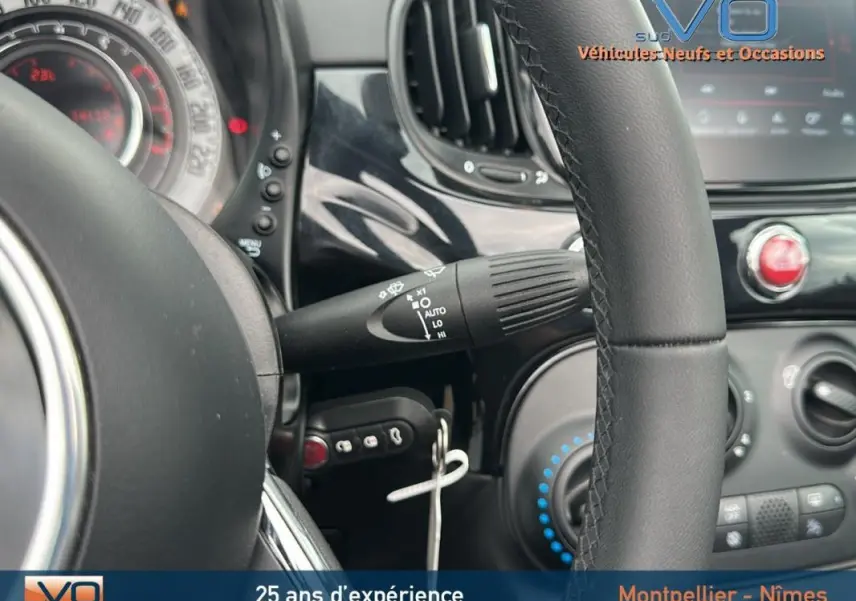 Vue rapprochée du volant et du tableau de bord noir de la FIAT 500C 2024 avec commandes et aérateurs visibles.