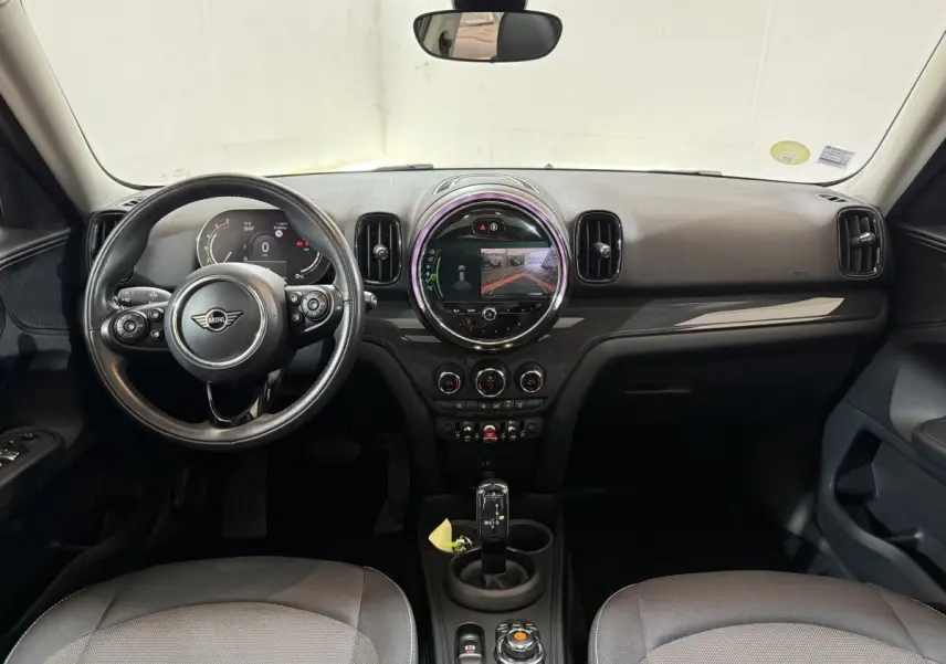 Vue frontale de l'intérieur noir du MINI Countryman 2020 avec volant cuir, écran tactile central rond et levier de vitesse automatique.