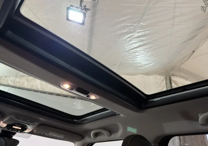 Toit panoramique ouvert vu de l'intérieur sur une MINI Countryman noire, mettant en valeur la luminosité naturelle.
