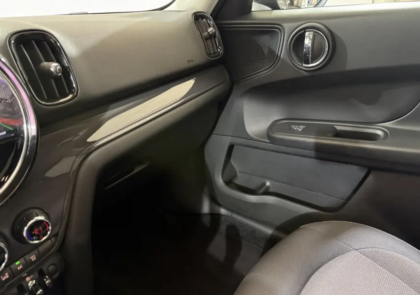 Vue intérieure côté passager du tableau de bord et porte d'une MINI Countryman noire, finition Business Design 2020.