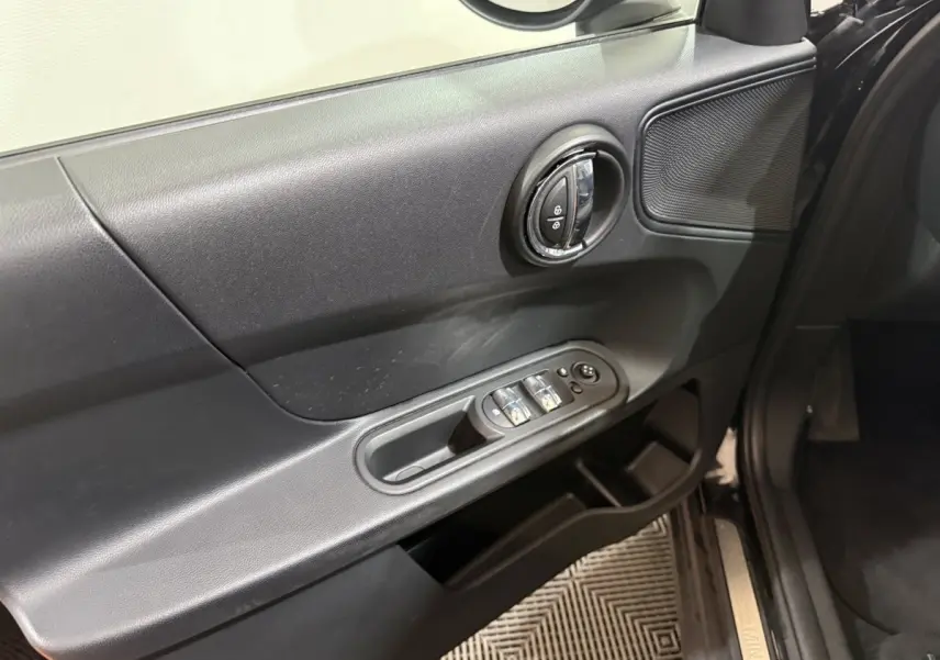 Vue rapprochée de la porte avant gauche noire d'une MINI Countryman 2020, avec commandes de vitres et serrure intégrée.