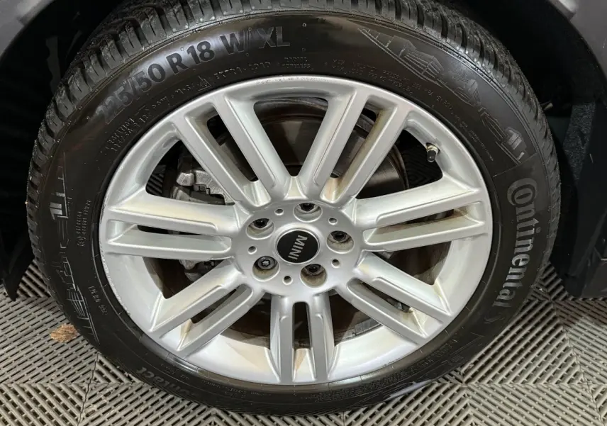 Gros plan sur la jante argentée et le pneu Continental d'un MINI Countryman noir, détail de la roue avant droite.