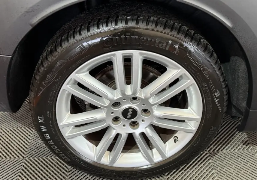 Gros plan sur la roue avant droite d'une MINI Countryman noire, jante alliage argentée et pneu Continental.