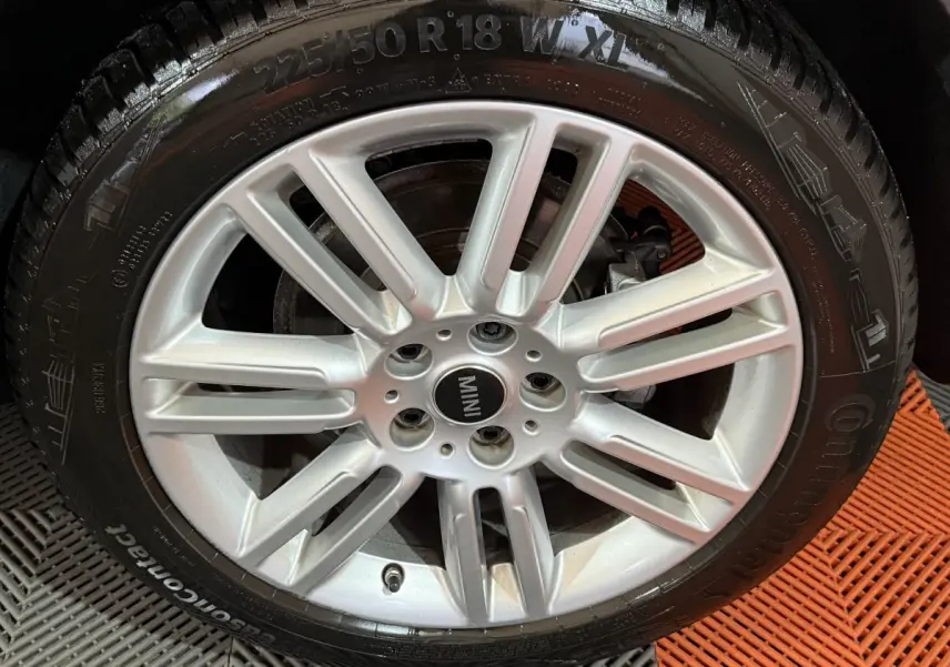 Gros plan sur la jante argentée à dix branches d'une MINI Countryman noire, avec pneu Continental visible.