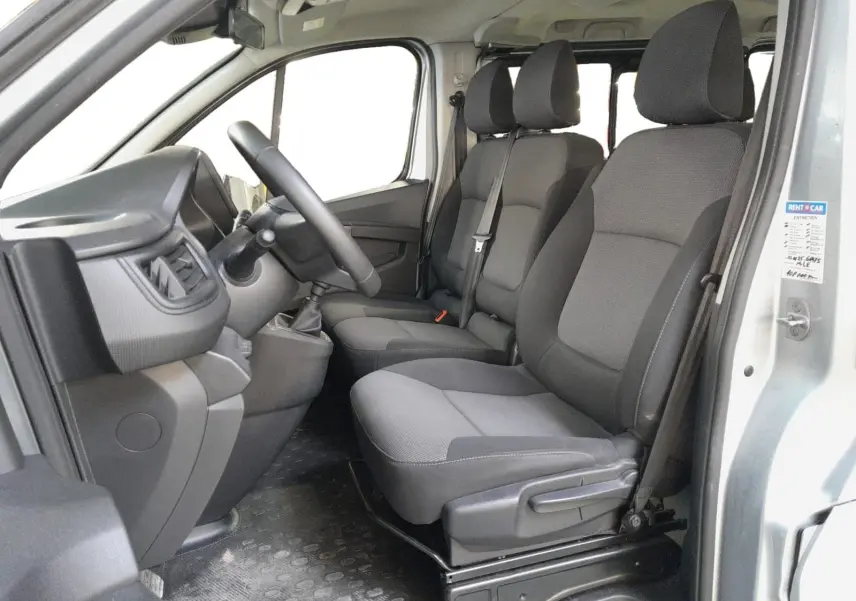 Vue intérieure côté conducteur du Renault Trafic Combi 2022, montrant les sièges gris et le tableau de bord simple.