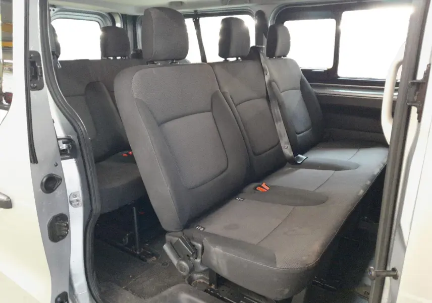 Vue intérieure côté droit des sièges passagers noirs du Renault Trafic Combi gris Highland avec porte coulissante ouverte.