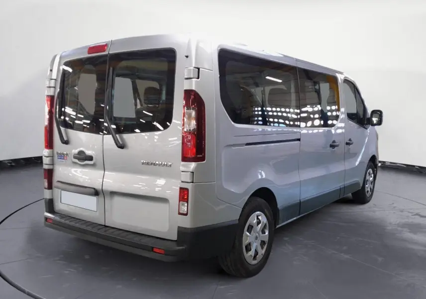 Vue 3/4 arrière droit d’un Renault Trafic Combi gris Highland, avec grandes vitres latérales et portes arrière vitrées.