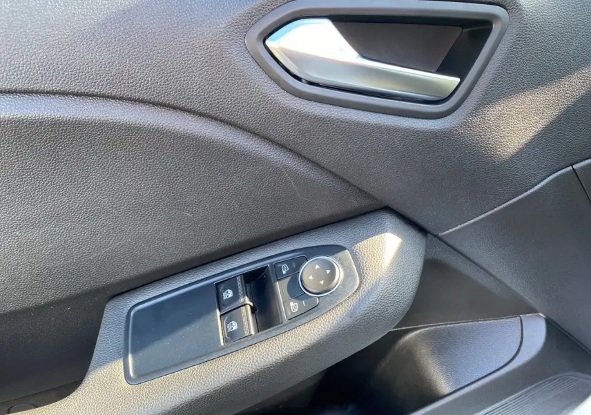 Gros plan sur la commande des vitres et rétroviseurs côté conducteur de la Renault Clio V E-Tech 140 Business en intérieur noir.