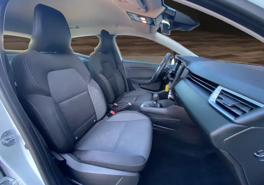 Vue intérieure côté gauche de la Renault Clio V blanche, montrant les sièges noirs et la planche de bord moderne.