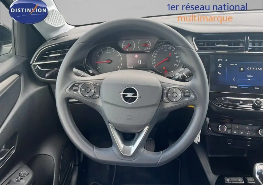 Vue intérieure centrée sur le volant multifonctions d'une Opel Corsa gris, avec tableau de bord et écran tactile visibles.