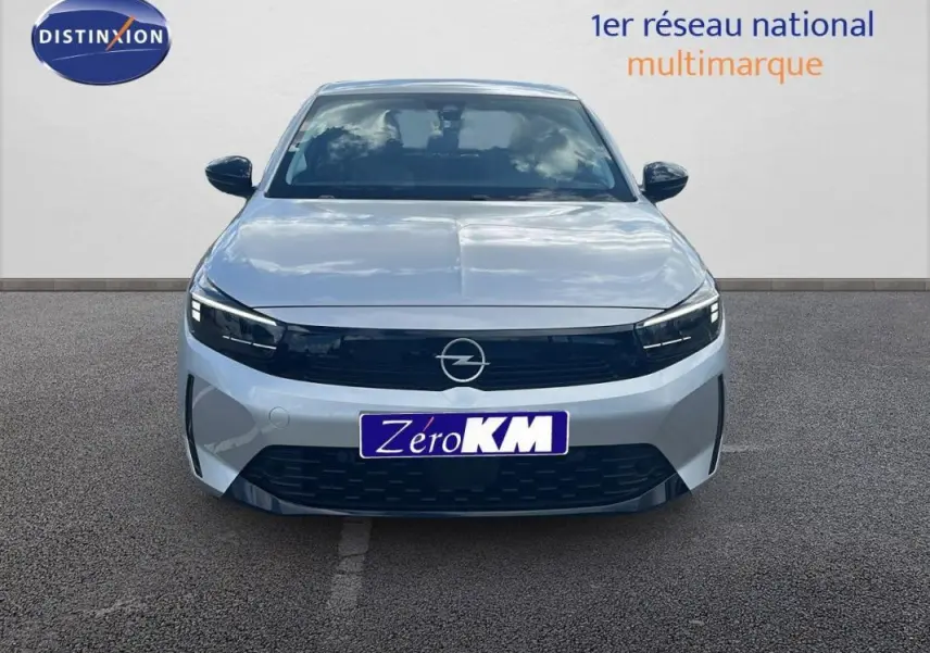 Vue frontale d'une Opel Corsa gris clair 2025 avec calandre noire et phares LED fins sur parking.