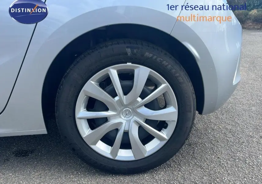 Gros plan sur la roue avant droite grise d'une Opel Corsa 2025 avec jante alu et logo Opel au centre.