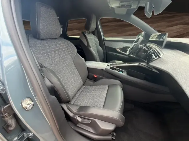 Vue intérieure côté conducteur du Peugeot 3008 bleu 2025, montrant sièges tissu et cuir, tableau de bord et écran tactile.