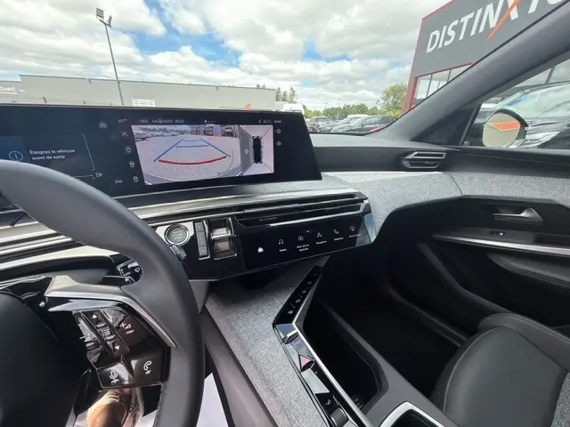 Vue intérieure côté conducteur du Peugeot 3008 bleu 2025, écran tactile affichant l'aide au stationnement arrière.