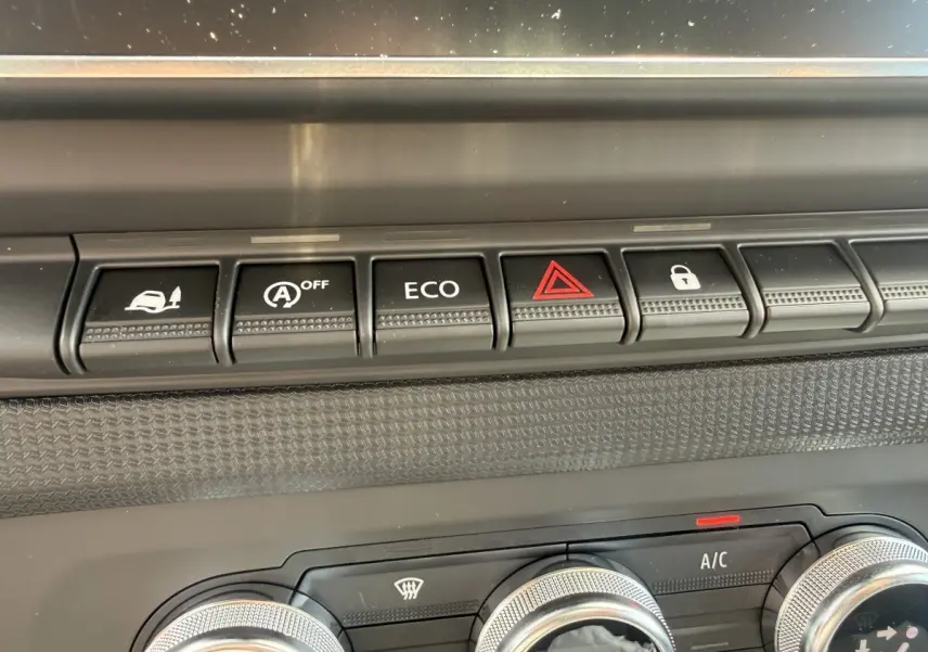 Gros plan sur la rangée de boutons de commande noire et les réglages de climatisation du tableau de bord du Renault Trafic blanc.