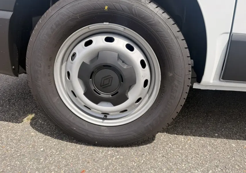 Gros plan sur la roue avant droite du Renault Trafic Fourgon blanc, mettant en valeur la jante acier et le logo central.