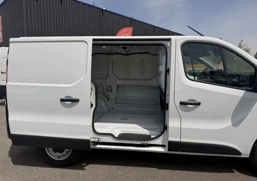 Vue latérale droite du Renault Trafic Fourgon blanc 2025 avec porte coulissante ouverte montrant l’espace de chargement vide.