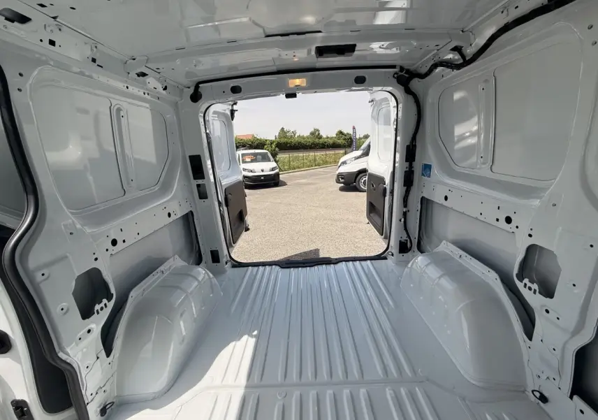 Vue intérieure arrière du Renault Trafic Fourgon blanc 2025, montrant l’espace de chargement vide et les portes ouvertes.