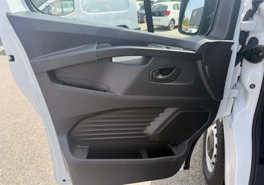 Vue de profil de la porte avant gauche ouverte du Renault Trafic Fourgon blanc, avec panneau intérieur noir et haut-parleur intégré.