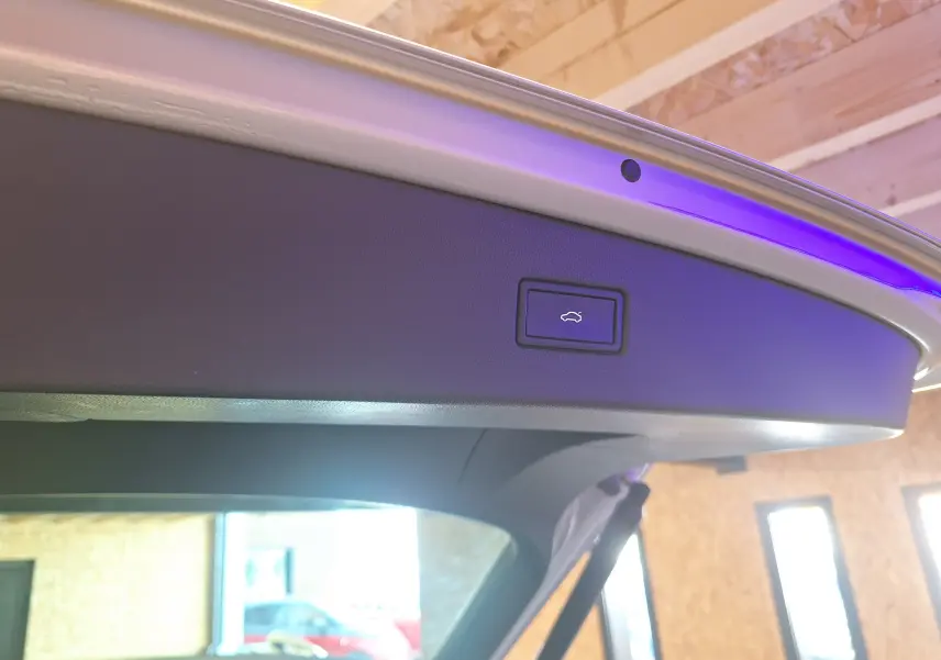 Bouton d'ouverture électrique du coffre sur le hayon intérieur du Volkswagen Tiguan gris 2021, éclairage d'ambiance violet visible.