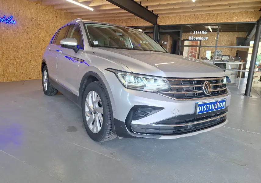 Volkswagen Tiguan gris métallisé vu de 3/4 avant droit avec jantes alliage et calandre chromée en showroom.