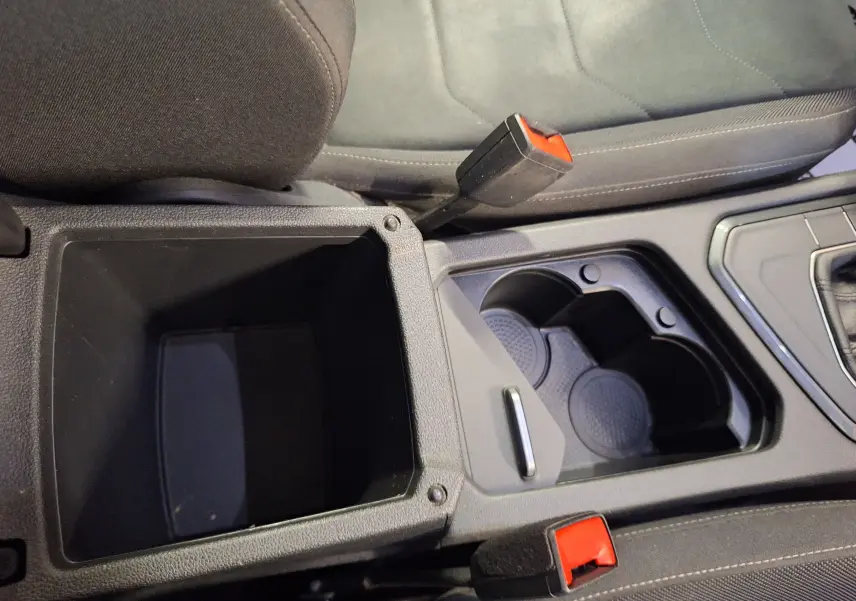 Gros plan intérieur sur la console centrale du Volkswagen Tiguan gris, avec porte-gobelets et frein à main rouge visible
