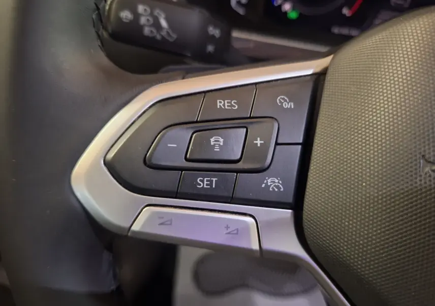 Gros plan sur les commandes du régulateur adaptatif au volant cuir du Volkswagen Tiguan gris 2021 finition Elegance.