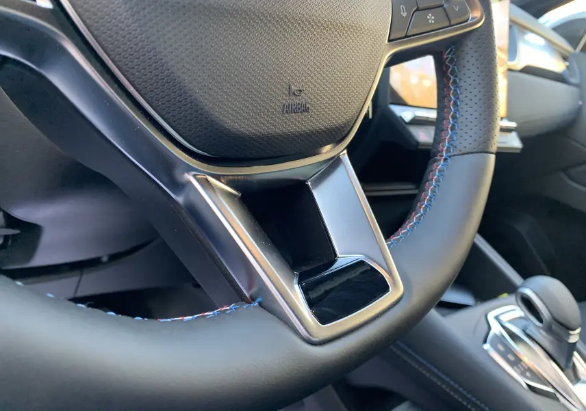 Gros plan sur le volant en cuir noir avec surpiqûres tricolores du Renault Symbioz E-Tech Full Hybrid 2025.