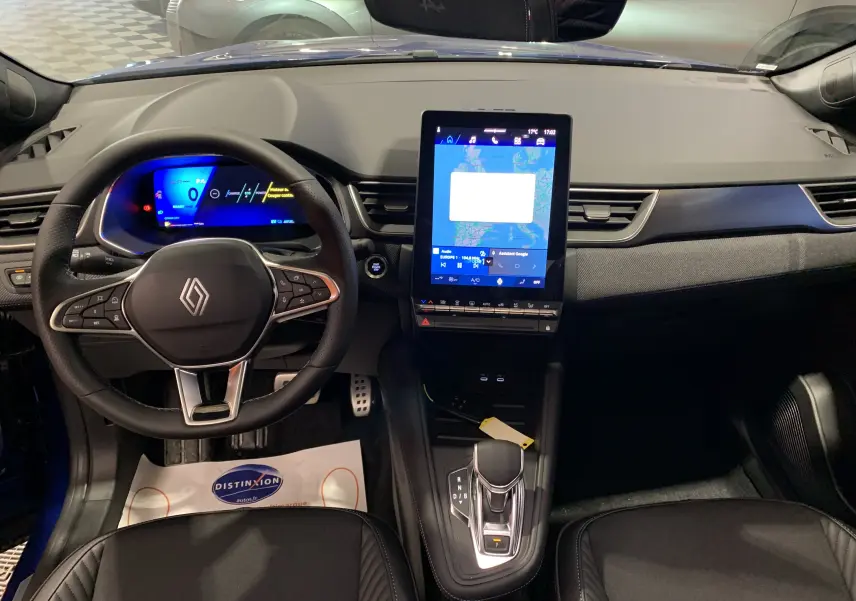 Vue intérieure avant du Renault Symbioz bleu iron, tableau de bord moderne avec écran tactile vertical et volant multifonction.