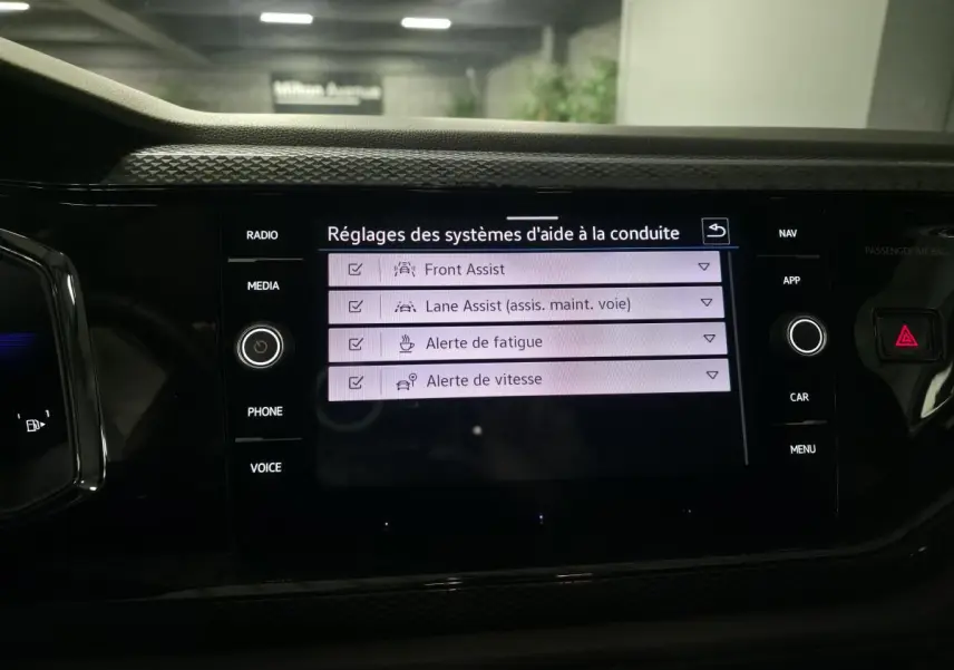 Écran tactile central de la Volkswagen Polo 2025 affichant les réglages d’aides à la conduite, intérieur noir.