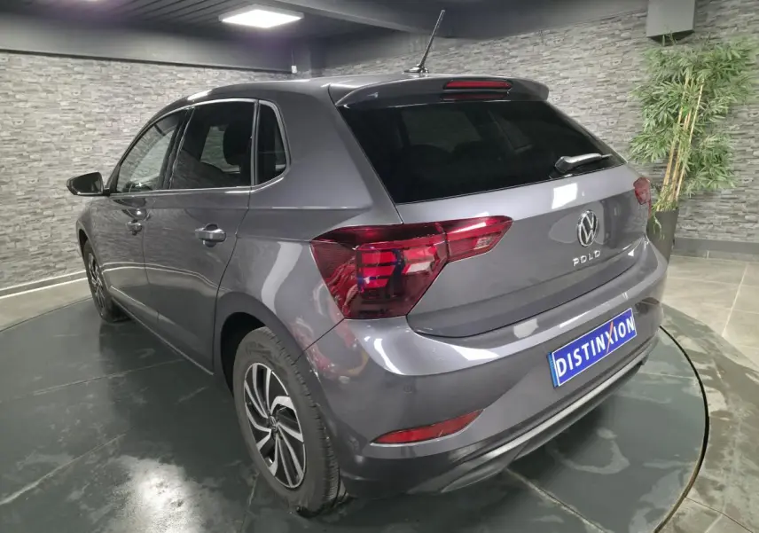 Vue 3/4 arrière gauche d'une Volkswagen Polo gris métallisé avec jantes alliage et vitres surteintées.