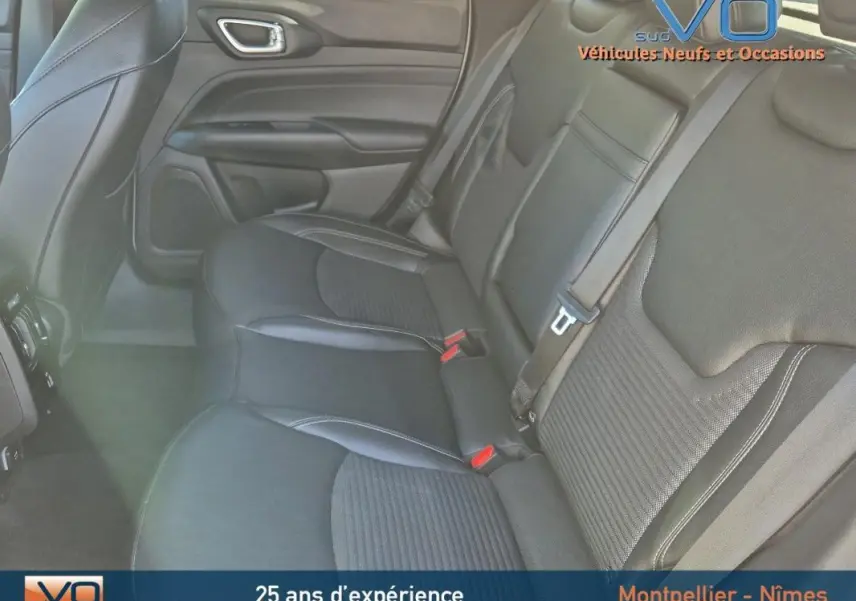 Vue intérieure arrière droite des sièges en cuir noir du Jeep Compass 2023 avec ceinture de sécurité et accoudoir central visible.