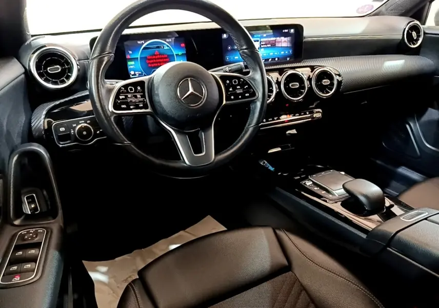 Intérieur noir de la Mercedes Classe A 250 e Business Line 2020, vue du poste de conduite avec tableau de bord numérique et volant cuir.