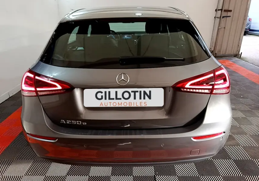 Vue arrière d'une Mercedes Classe A 250 e Business Line gris foncé avec feux arrière LED allumés dans un garage.