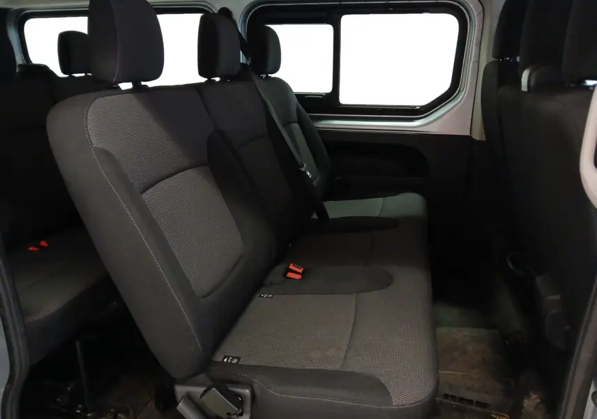 Vue intérieure côté droit des sièges arrière gris foncé du Renault Trafic Combi L2 2023, avec fenêtre latérale visible.