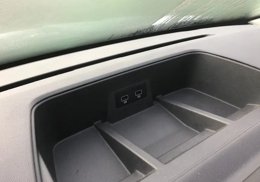 Gros plan sur le rangement central du tableau de bord du Renault Trafic Combi gris clair, avec deux ports USB visibles.