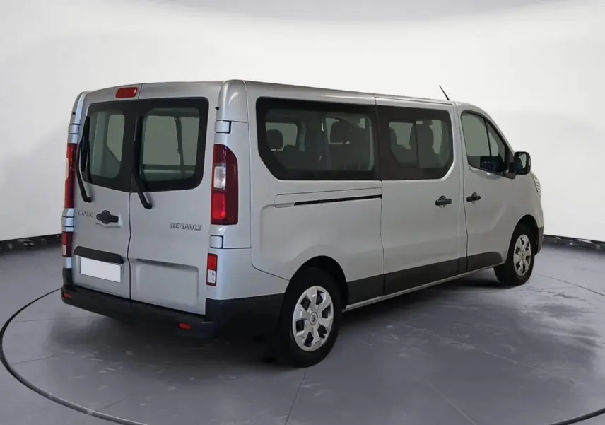 Vue 3/4 arrière droite d'un Renault Trafic Combi gris clair métal, avec vitres latérales et portes arrière vitrées.