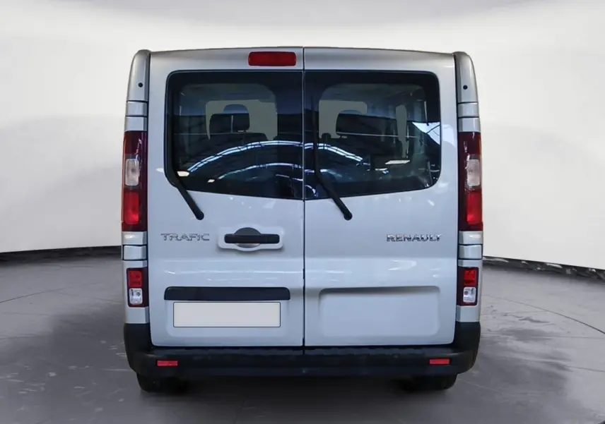 Vue arrière d’un Renault Trafic Combi gris clair métal, portes battantes avec essuie-glaces et feux verticaux rouges.