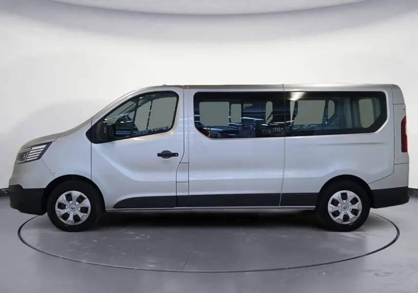 Profil droit d’un Renault Trafic Combi gris clair métal 2023, grand fourgon avec vitres latérales et jantes acier.