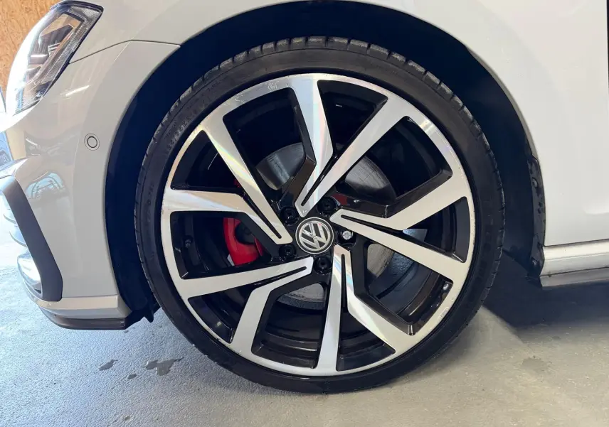 Vue intérieure côté gauche montrant les sièges sport à motif tartan et coutures rouges d'une Volkswagen Golf GTI Performance gris clair.