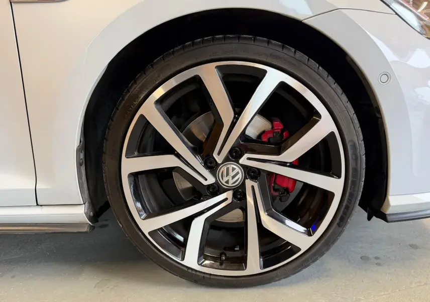 Vue intérieure du panneau de porte côté conducteur de la Volkswagen Golf GTI Performance gris, avec commandes électriques et insert rouge.